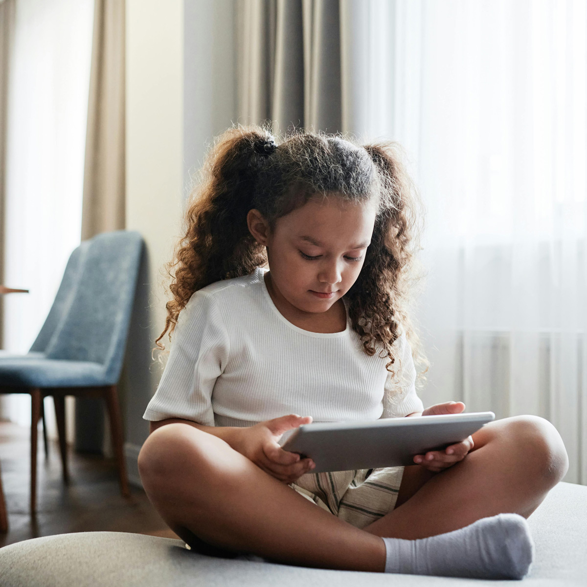 Photo of young girl with pigtails reading on a tablet